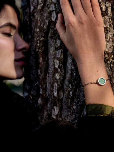 femme qui enlace un arbre avec un bracelet chaîne or blanc Uchéal en malachite - Joaillerie éthique