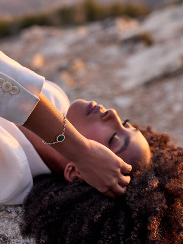 Jolie femme allongée sur la roche portant au poignet un bracelet chaine or Uchéal en lapis lazuli